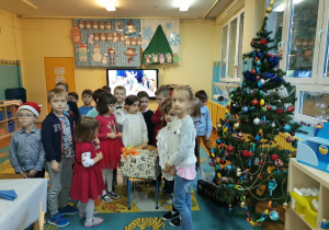 Dzieci pozują do zdjęcia z zapakowanym prezentem